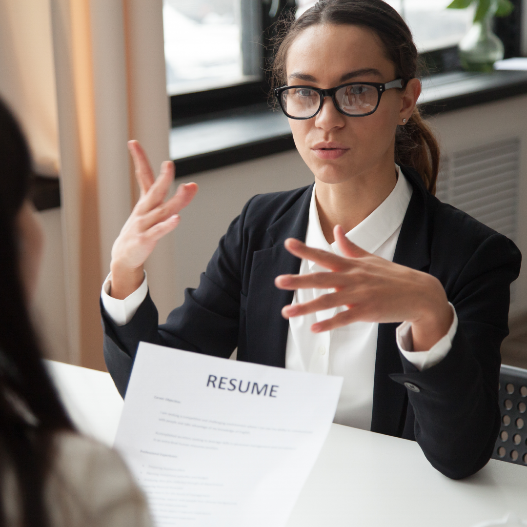 A woman in glasses engages in conversation with another woman, discussing reiki healing for career and job interviews.
